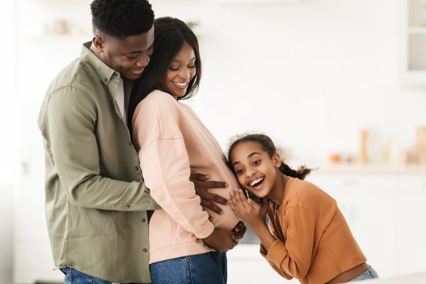 happy black family hugging expecting baby in kitchen at home