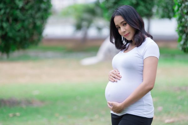 portrait of asian beautiful pregnant woman at the parkthailand peoplehappy woman concepther use hand touch her bellymother day concept